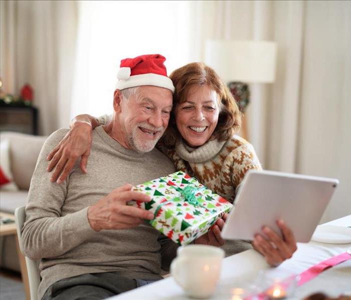 Vista frontal de la pareja mayor en casa en Navidad transmitiendo en su tableta.