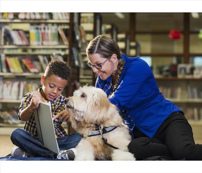 Service dog in library with woman and child